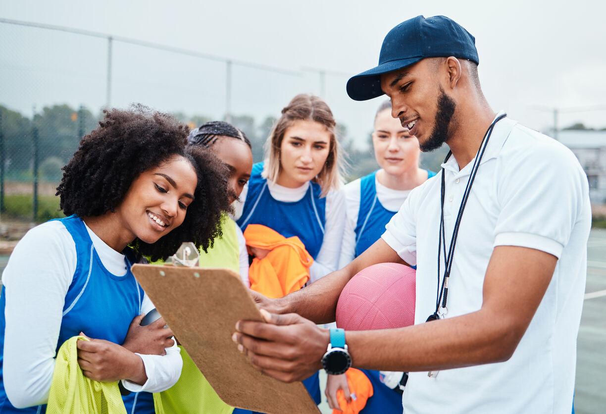 high school female coach showing a book to her team