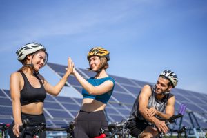 Cycling Schedule for 80 Miles Per Week - two white female cyclists giving each other high five wile the male looked on