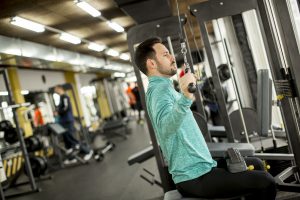 exercise machines - white guy exercising on a cable machine